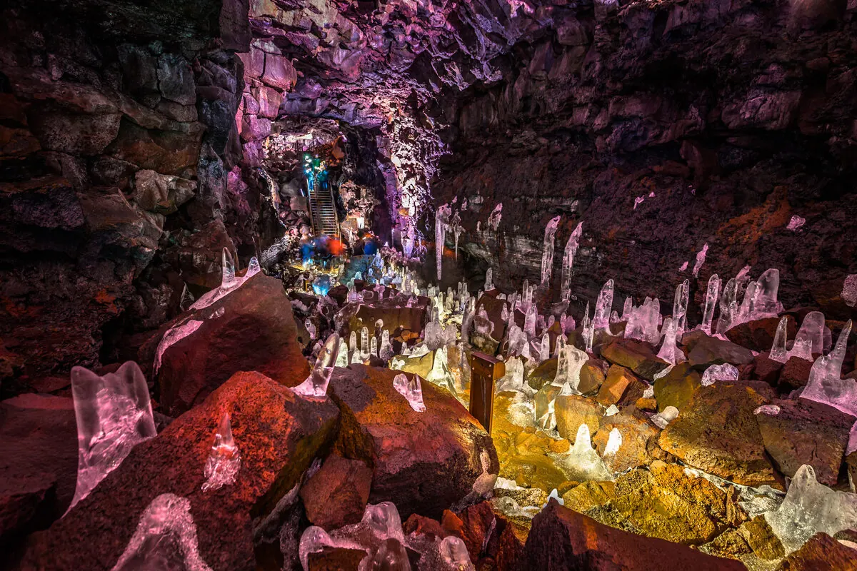 Rows of translucent ice formations lit in pink and gold along the tunnel floor