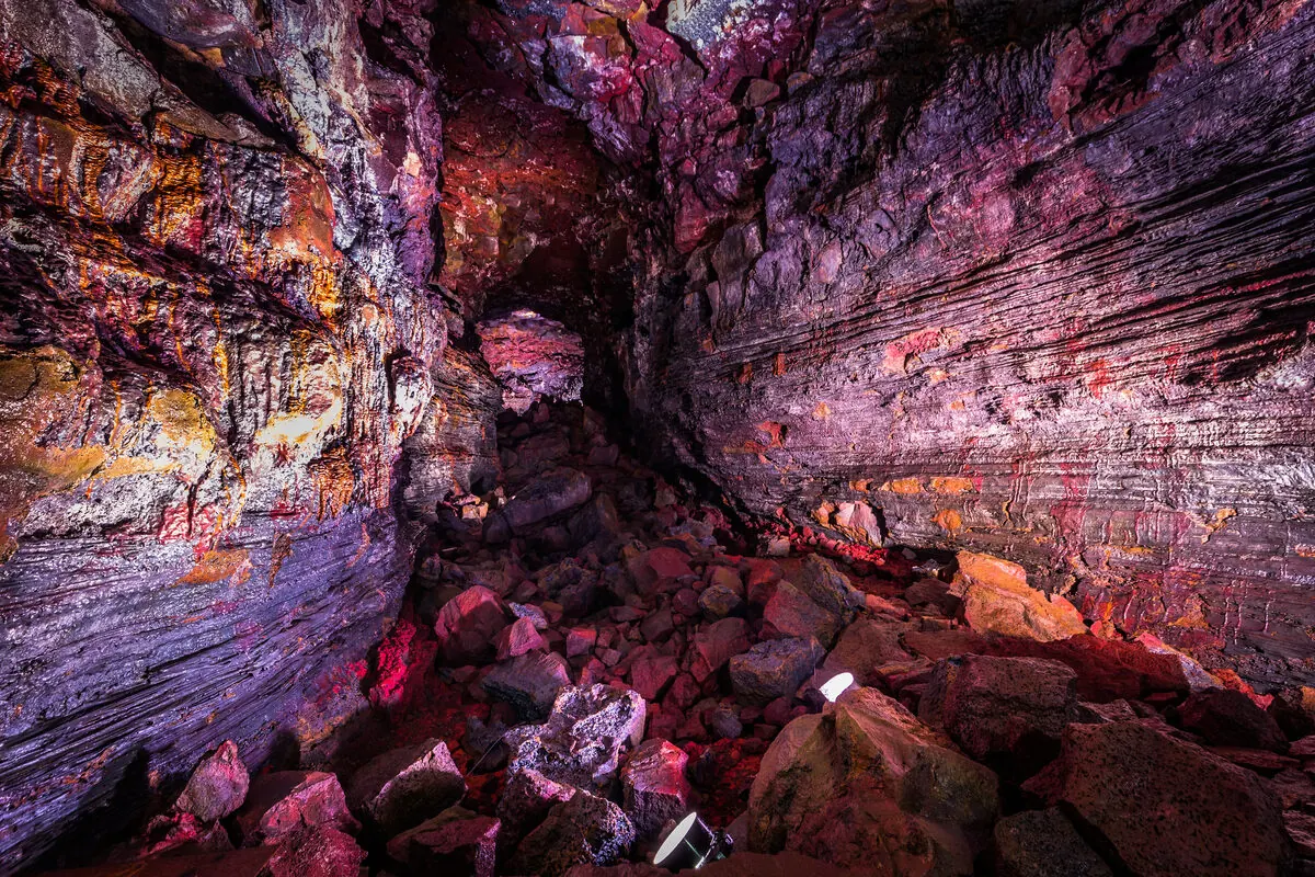 Wide view of the tunnel's ridged rock walls lit in purple and amber