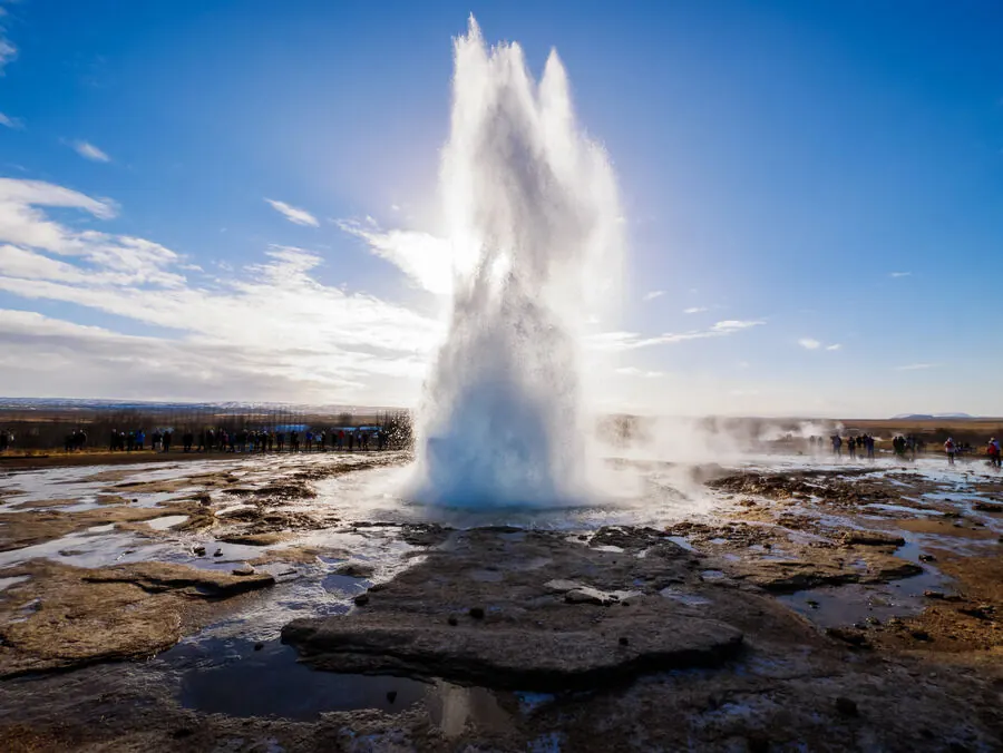 Strokkur geyser erupting into a double plume against a blue sky