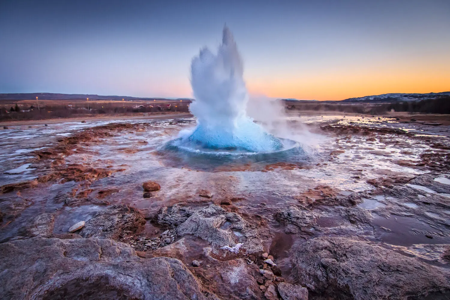 Strokkur geyser erupting at sunset with a colourful sky