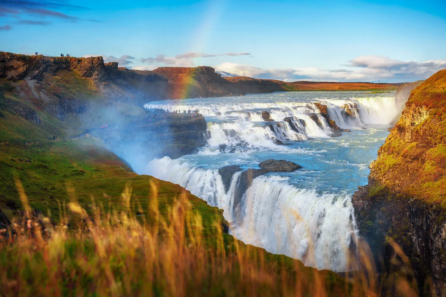 A rainbow arcing over Gullfoss waterfall on Iceland's Golden Circle route, seen from above the canyon
