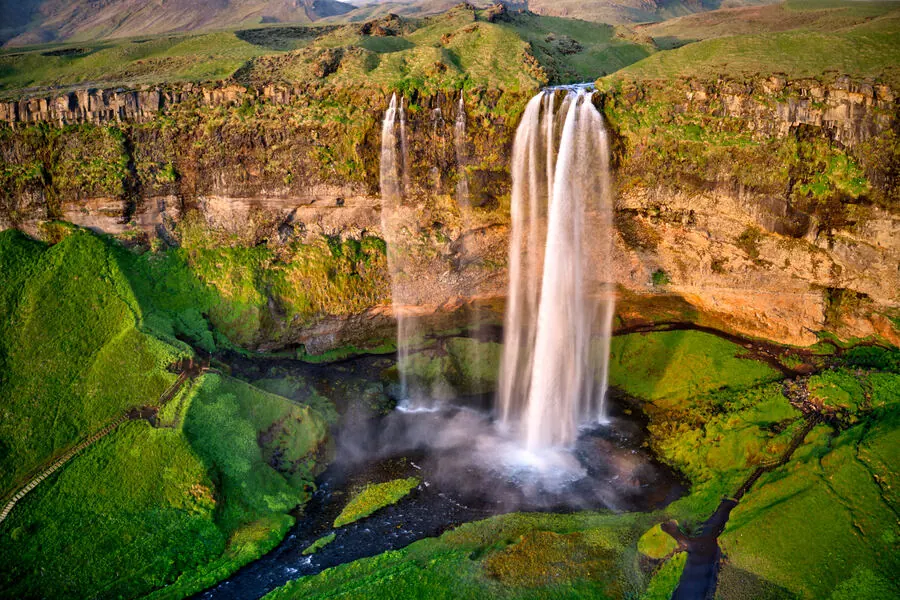 Aerial view of Seljalandsfoss waterfall with its walking path circling behind the falls