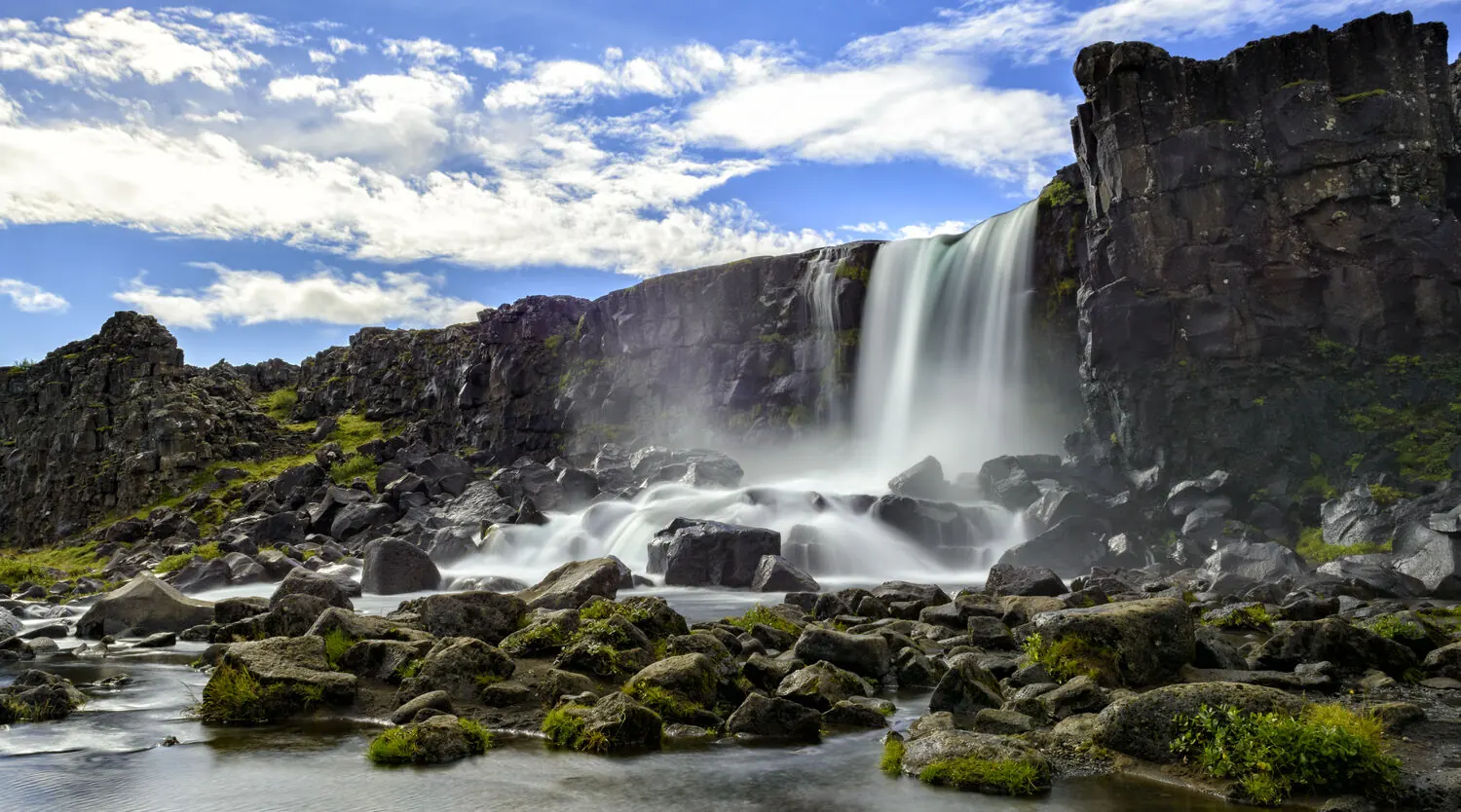 Öxarárfoss waterfall tumbling over black rock at Þingvellir