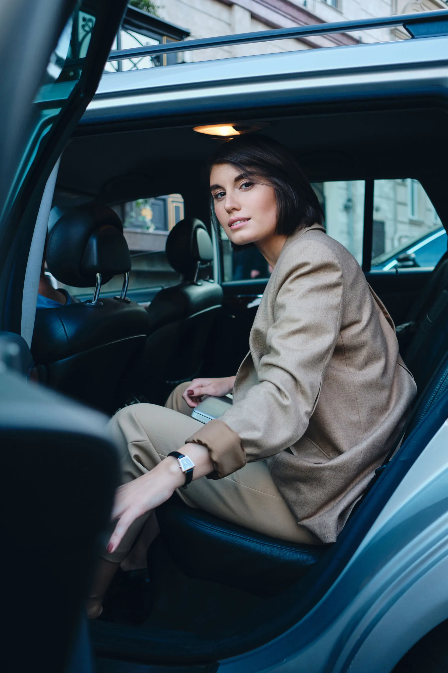 A woman settling into the back seat of a premium car