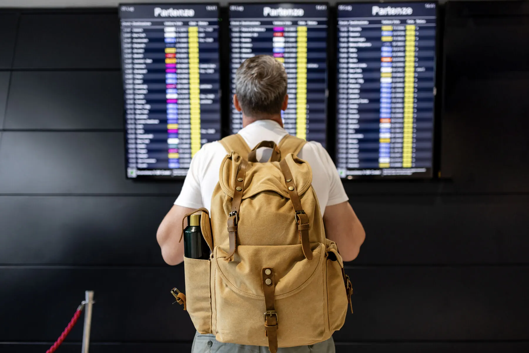 A traveler with a backpack checking a departures board at the airport