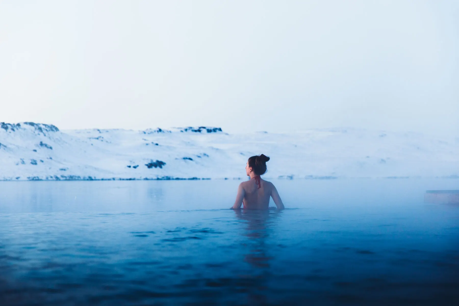 A bather relaxing in steaming milky-blue water
