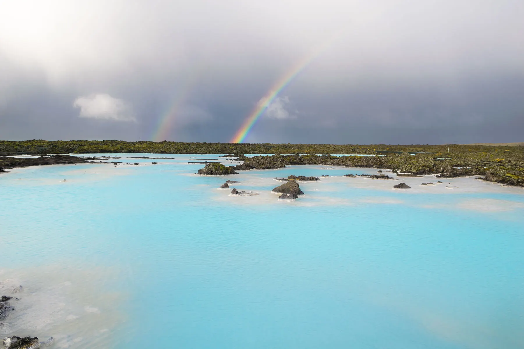 A rainbow over a steaming geothermal lagoon
